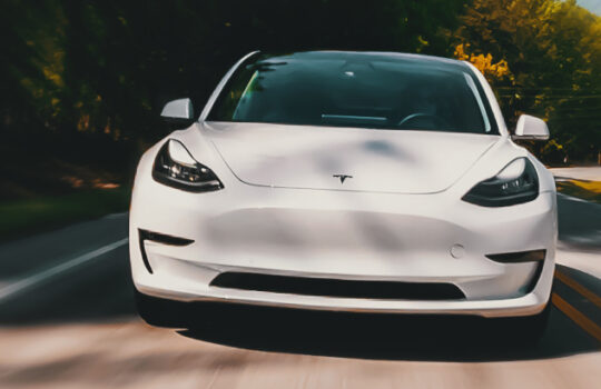 A new Tesla Model 3 all electric vehicle driving down a country road