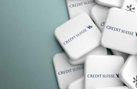 Logos of Credit Suisse and UBS Bank on a heap on a table. Concept for a possible merger or take over. Copy space. Web banner format.