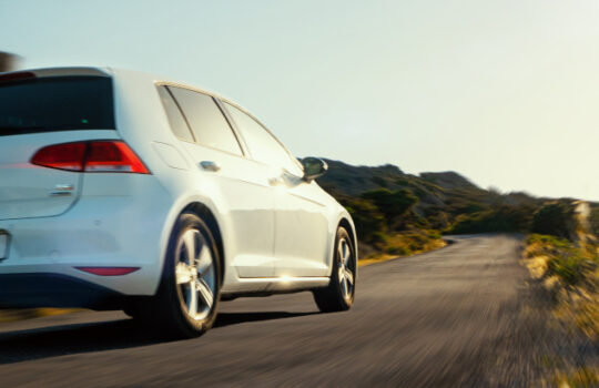 fast driving VW Golf rental car in spain mountain landscape road at sunset