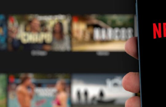 Male hand holding a smartphone with Netflix App on the screen with de website blurred on background. Rio de Janeiro, RJ, Brazil. August 2021.