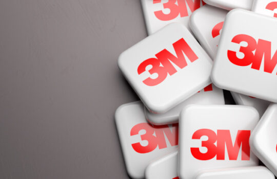 Logos of the multinational conglomerate company 3M on a heap on a table. Copy space. Web banner format.