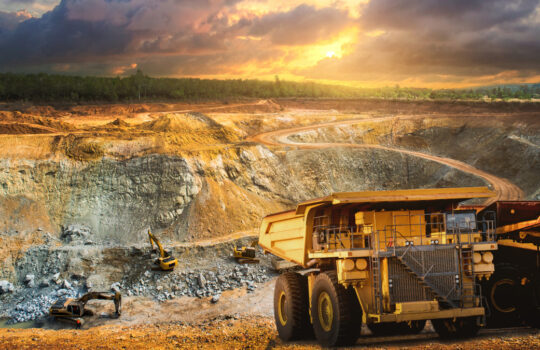 Yellow dump truck loading minerals copper, silver, gold, and other at mining quarry.