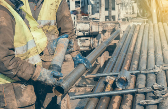 Drill core worker hands holding core sample of sandstone layer from drill hole. Made with shallow dof and vintage style.