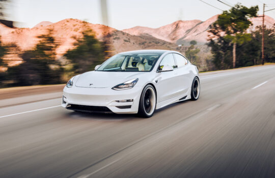 Weißer Tesla Model 3 fährt mit hohem Tempo auf einer US-Bundesstraße. AdobeStock_569003359_Editorial_Use_Only