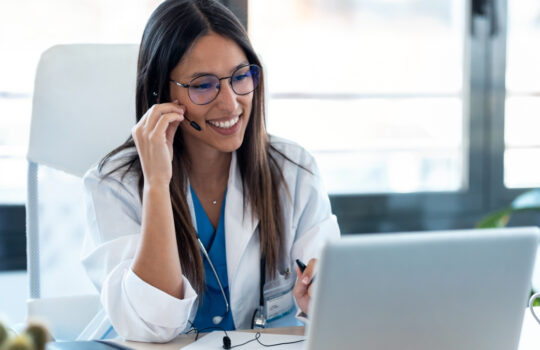 Shot of female doctor talking with colleagues through a video call with a laptop in the consultation.