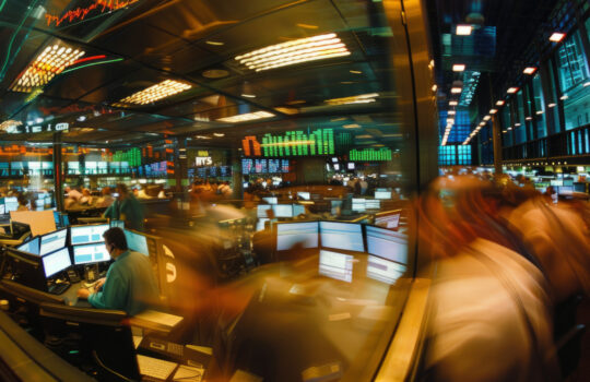 A bustling stock exchange trading floor filled with brokers and traders working diligently at their computer stations