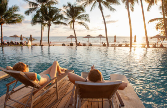 honeymoon couple relaxing in beach hotel near swimming pool at sunset, dream holidays
