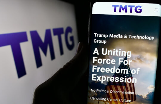 Stuttgart, Germany - 02-22-2024: Person holding cellphone with webpage of US company Trump Media Technology Group (TMTG) in front of logo. Focus on center of phone display.