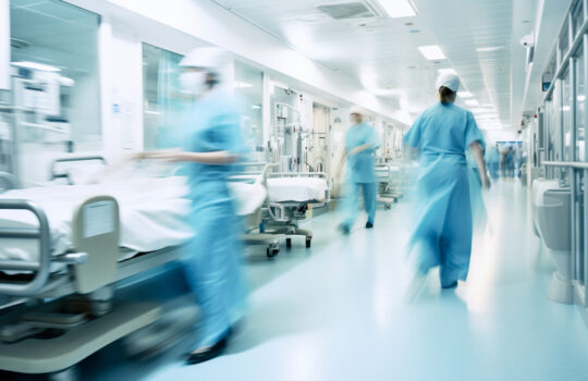 Long exposure blurred motion of medical doctors and nurses in a hospital ward wearing blue aprons, walking down a corridor - Generative AI