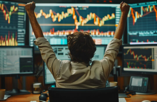business man congratulations stock trader sitting at a desk in front of computer monitors