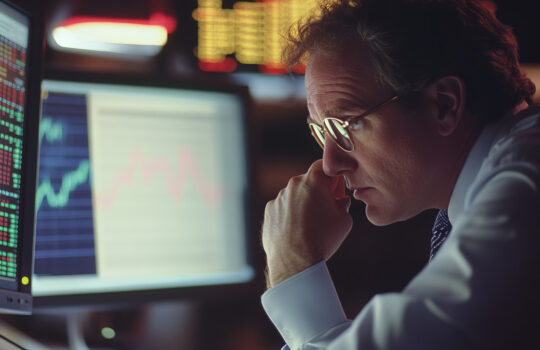 Hand of a stock broker analysing line graph on computer screen