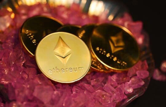 two gold coin sitting on top of a pile of pink crystals