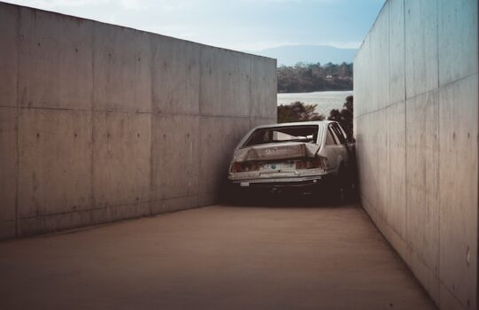 wrecked gray vehicle between concrete walls at daytime