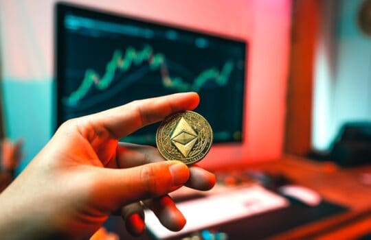 a person holding a coin in front of a computer