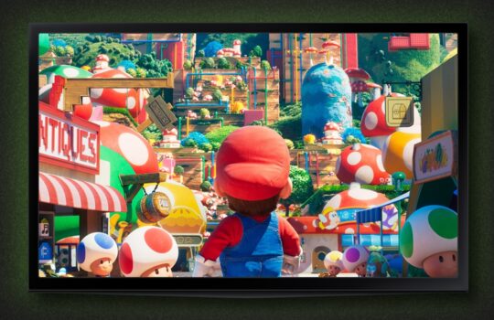 Mario-style character in red hat and blue overalls stands in a colorful toy-city street with oversized mushrooms behind him/ her.