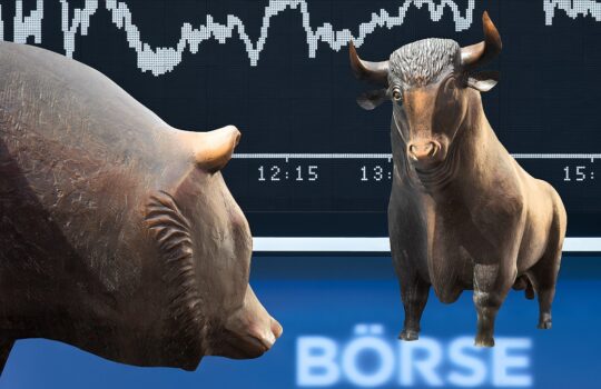 Bull and bear statues facing each other in front of a stock market display with a price chart backdrop and 'BÖRSE' text (stock market scene)