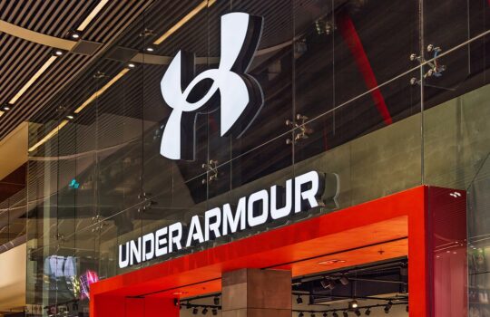 Under Armour storefront with large white logo and bold sign on a glass facade in a mall.