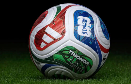 Soccer ball with colorful FIFA branding resting on green grass at night