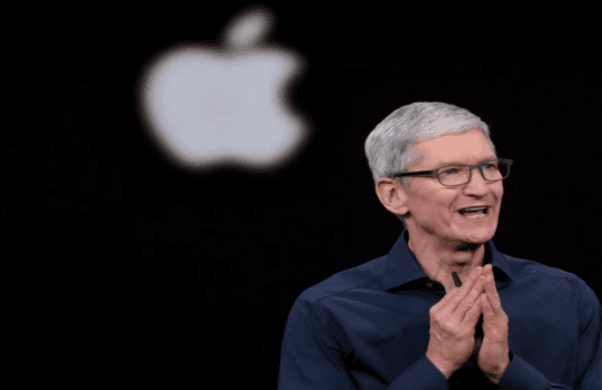 Tim Cook, Apple CEO, speaking on stage with a large Apple logo behind him.