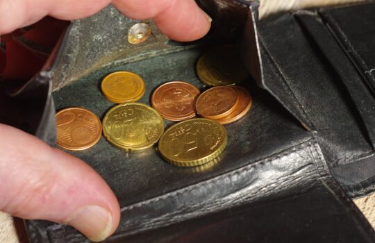 Hand placing coins into a black leather wallet.