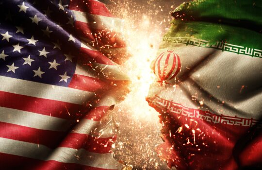 US and Iran flags collide with fiery sparks in the center, symbolizing confrontation or clash