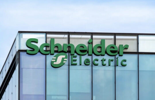 Schneider Electric logo on a modern glass office building facade in blue sky background