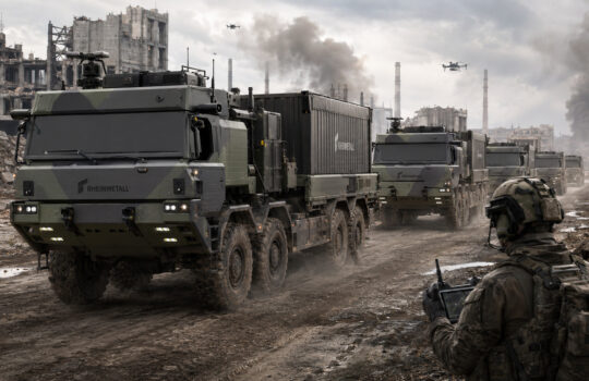 Military convoy of rugged armored trucks labeled Rheinmetall carries a large container through a bombed urban landscape with smoke and ruins nearby.