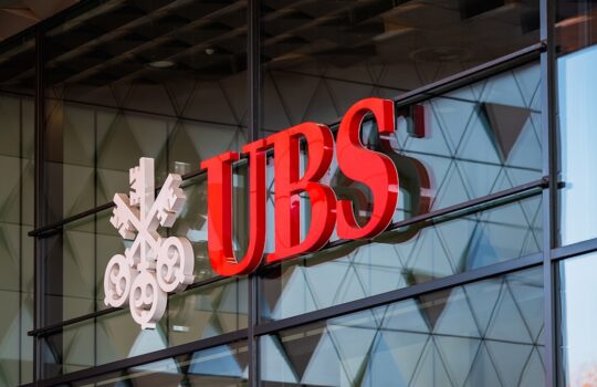 UBS logo in red on a glass building, with a white snowflake symbol beside it.