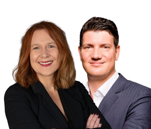 Two smiling professionals, a woman and a man, pose together in business attire against a white background.