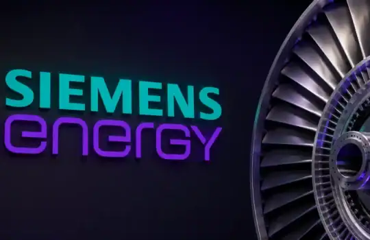 Siemens Energy logo in teal and purple glow on a dark wall, with a close-up of a large metal turbine on the right.