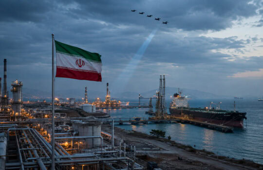 Iranian flag waving above an oil refinery by the sea at dusk