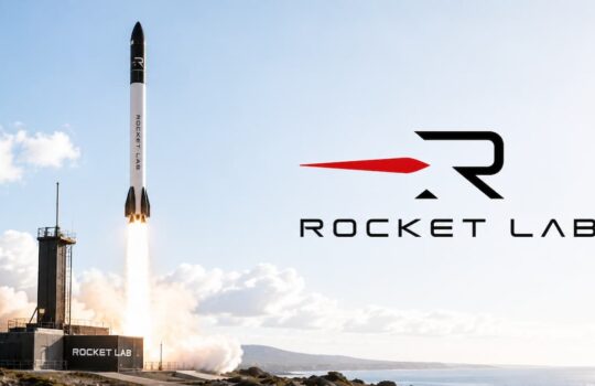 Rocket Lab rocket launches from a coastal launch pad, leaving a bright flame plume as the Rocket Lab logo appears on the right.