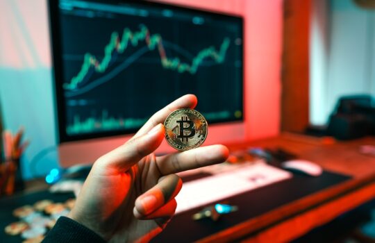 a person holding a coin in front of a computer