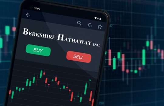 Smartphone showing Berkshire Hathaway Inc. trading app with green Buy and red Sell buttons over a stock chart.