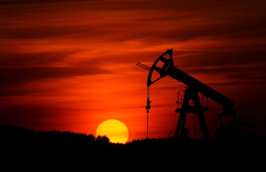 oil pump jack silhouette against red sunset