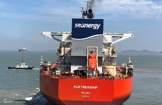 Red cargo ship named PARTNERSHIP with seanergy branding on the superstructure at sea, viewed from the stern.