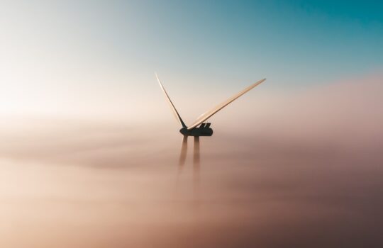 wind turbine emerging from fog at sunrise