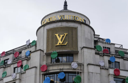 Louis Vuitton storefront with the gold LV logo and festive colorful balloons along the facade.