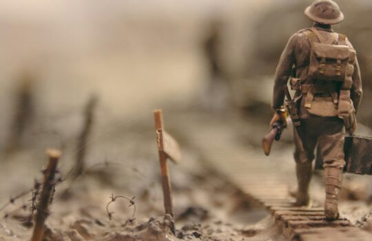 soldier walking on wooden pathway surrounded with barbwire selective focus photography